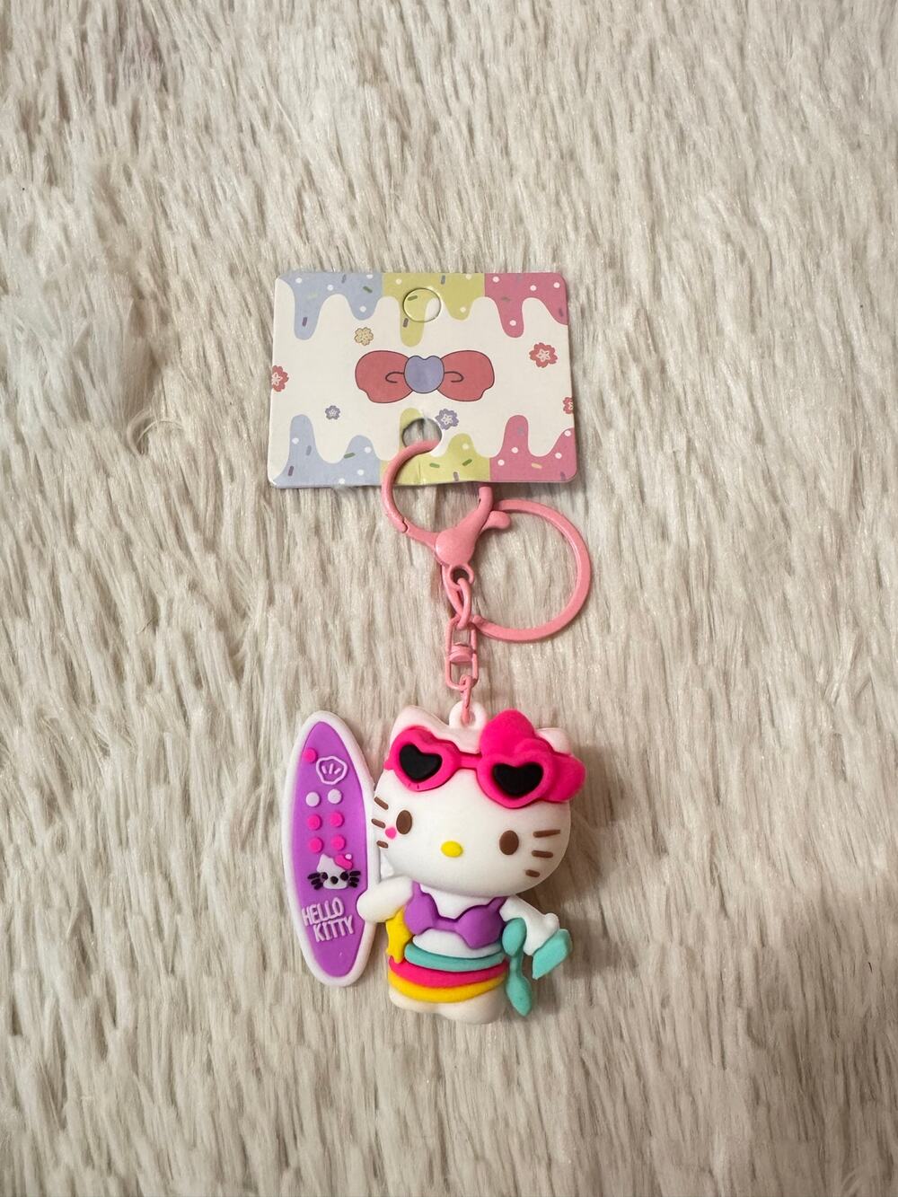 Hello Kitty Surfing Keychain holding surfboard rainbow swimsuit sunglasses